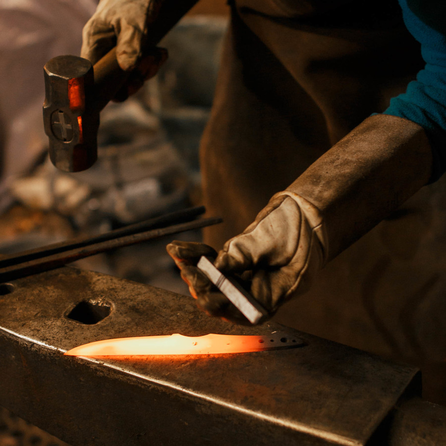 A red hot glowing knife sits atop an anvil.